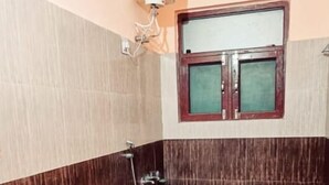 Un baño con inodoro, lavabo, ventana y ducha.