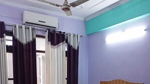 Un dormitorio con cama de madera, ventilador de techo, aire acondicionado y cortinas.