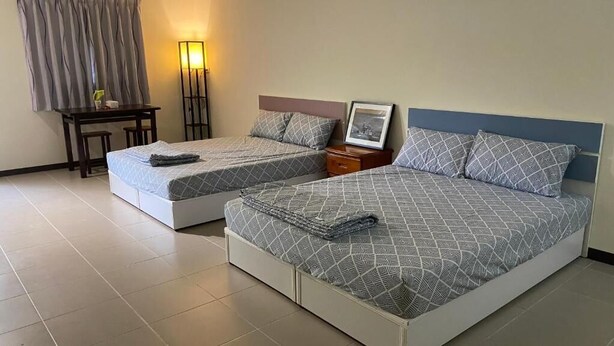Habitación de hotel con dos camas, un escritorio, una silla y una mesita de noche.