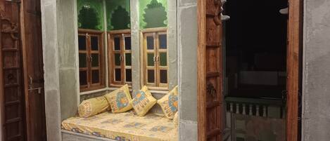 A room with a built-in window seat, wooden doors, and a view of the outside.
