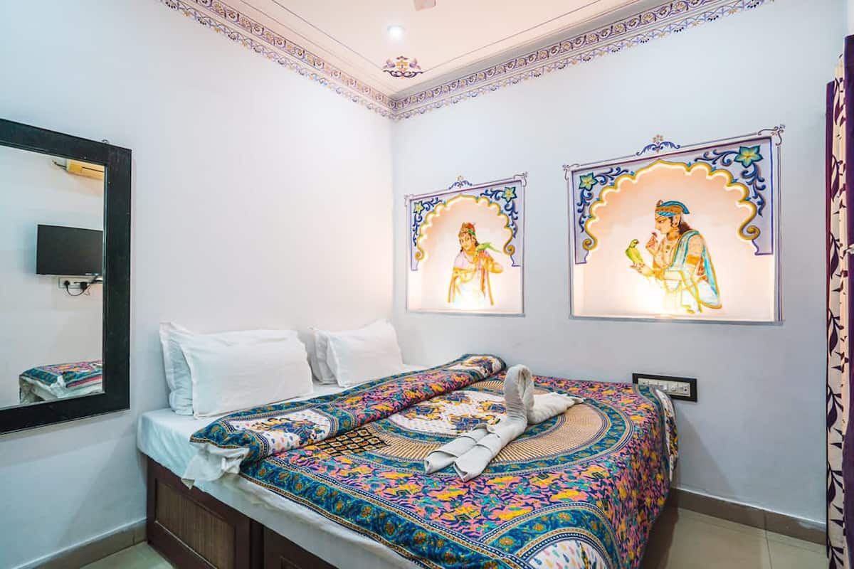A bedroom with a bed, a mirror, and two framed pictures on the wall.