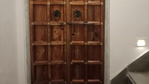 A wooden double door with a decorative top and metal hinges. - Lassi Guest House (Udaipur)