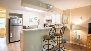 A modern kitchen with a refrigerator, stove, and bar stools.