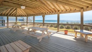 A wooden deck with picnic tables and a view of the ocean.