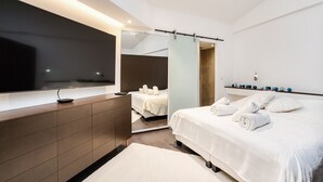 A modern hotel room with a large bed, a bedside table, a mirror, and a TV mounted on the wall. - Appartement Place des lices Avec Parking (Saint-Tropez)