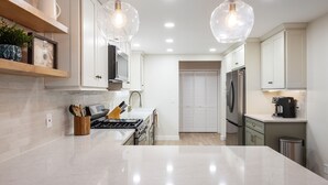 A modern kitchen with white cabinets, a marble countertop, and pendant lighting. - 1500 FT from Gowdy Shores Beach, Fire Pit (Union Pier)