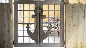 A wooden gate with a metal anchor design, leading to a yard with a fence and a vehicle in the background. - 1500 FT from Gowdy Shores Beach, Fire Pit (Union Pier)