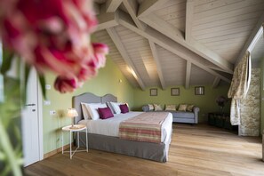 A bedroom with a wooden ceiling, a bed with a striped blanket, a bedside table with a lamp, and a sofa in the background. - Private Villa with A/C, WIFI, private pool, TV, patio, pets allowed, panoramic view, close to Alba (San Grato)