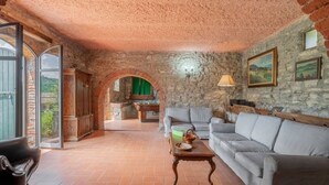 Ein rustikales Wohnzimmer mit Steinwand, Billardtisch, Sofa und Couchtisch.
