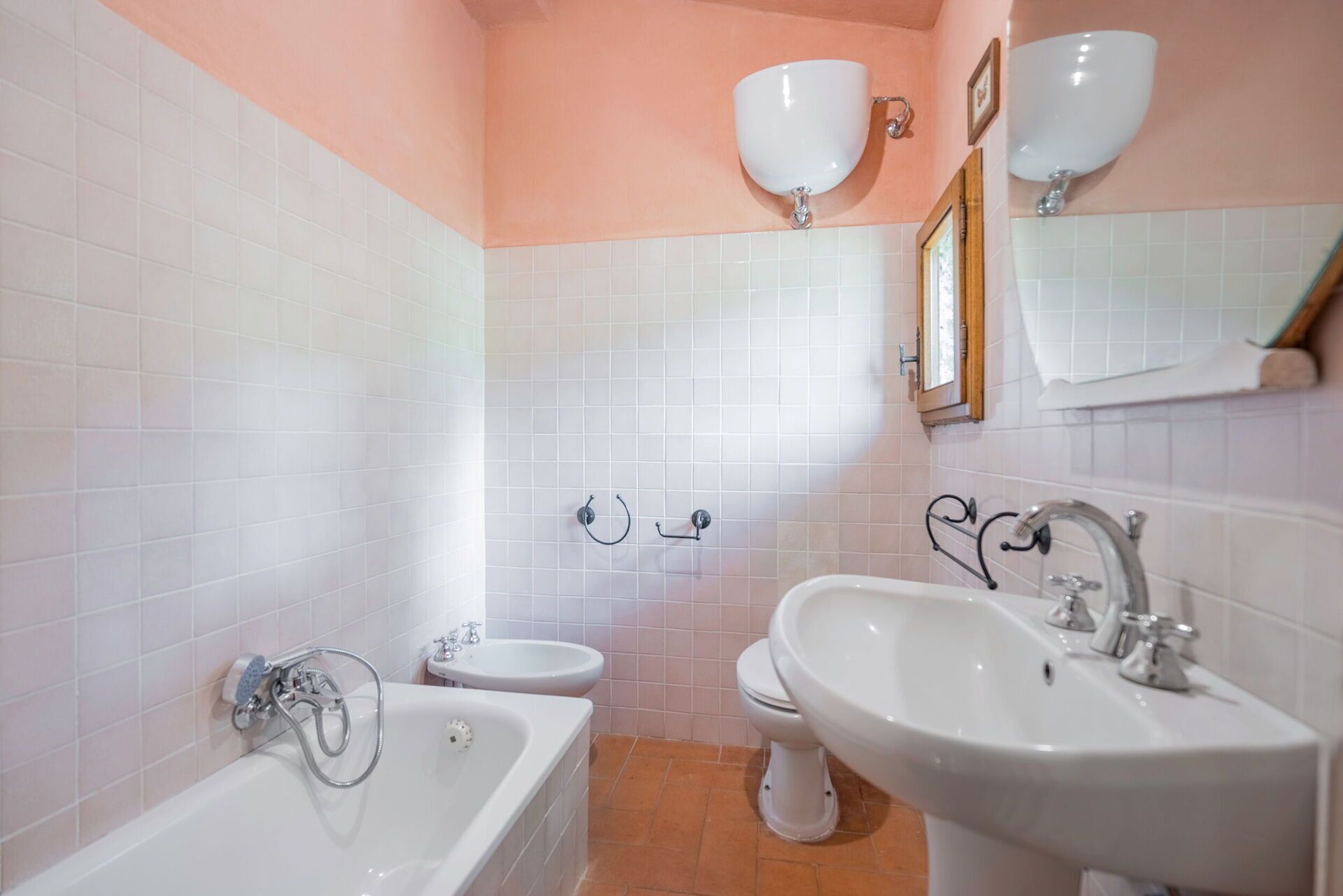 Een badkamer met een bad, wastafel, toilet en bidet.
