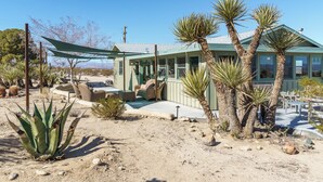 A desert-style house with a covered patio, outdoor furniture, and various desert plants.