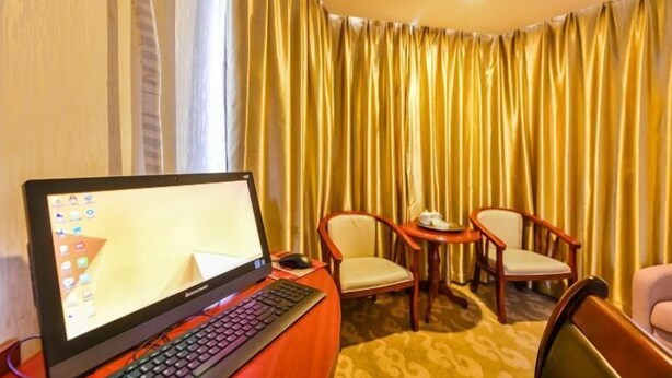 Habitación de hotel con escritorio, ordenador portátil, dos sillas y una mesita con una taza y un plato.