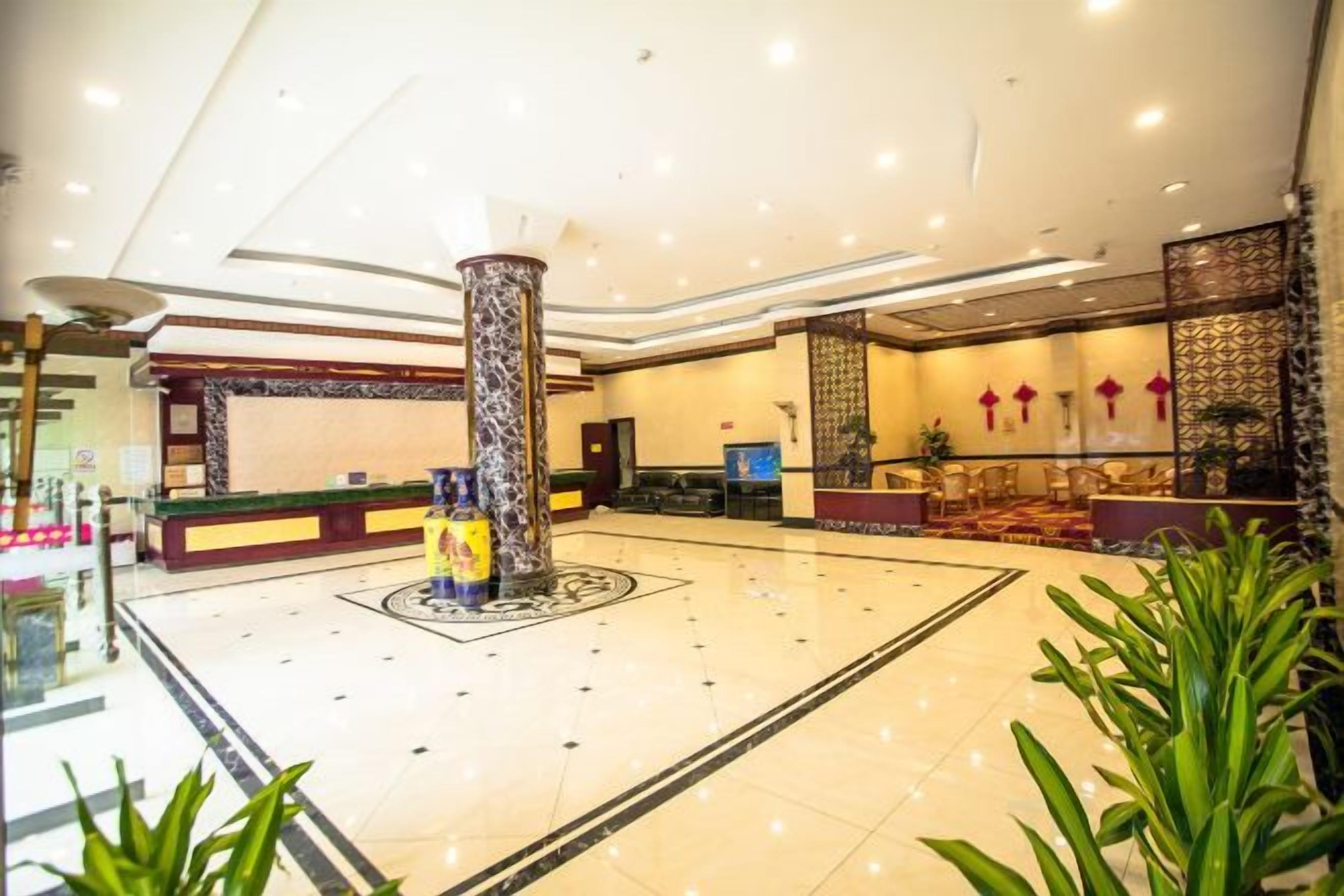 En hotellobby med en receptionsdisk, en stor pelare och en sittgrupp.