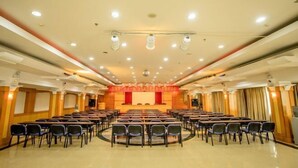 Une salle de conférence avec des rangées de chaises disposées face à une scène sur laquelle se trouve un pupitre.