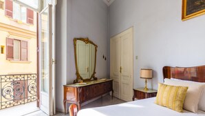 Une chambre à coucher avec un lit, une commode, un miroir, une table de chevet et une porte.