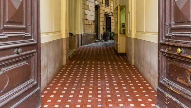 Un couloir avec des portes en bois richement décorées, un sol carrelé et un plafond blanc.