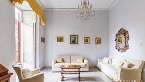 Un salon avec un ensemble de canapés de couleur beige, une table basse en bois, un lustre et des tableaux encadrés accrochés au mur.
