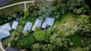 An aerial view of a residential area with multiple houses, surrounded by dense greenery and trees.