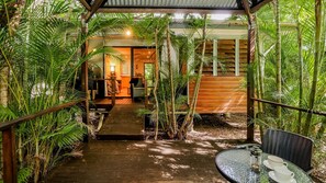 Un complexe hôtelier tropical doté d’une terrasse en bois donnant sur un espace abrité, équipé d’une table et de chaises.