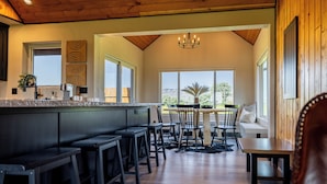 A modern kitchen with a bar area, large windows, and a view of the outdoors. - Cedar Mountain Retreat- Hot Tub, Pet Friendly, Mountain Views (Cody)