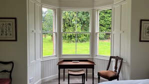 A corner room with a bay window overlooking a garden.