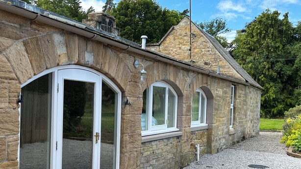 A stone building with arched windows and a gravel driveway.