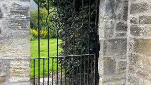 A stone wall with a metal gate featuring intricate designs.