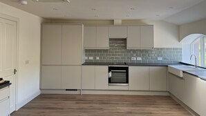 A modern kitchen with white cabinetry, a built-in oven, and a skylight.