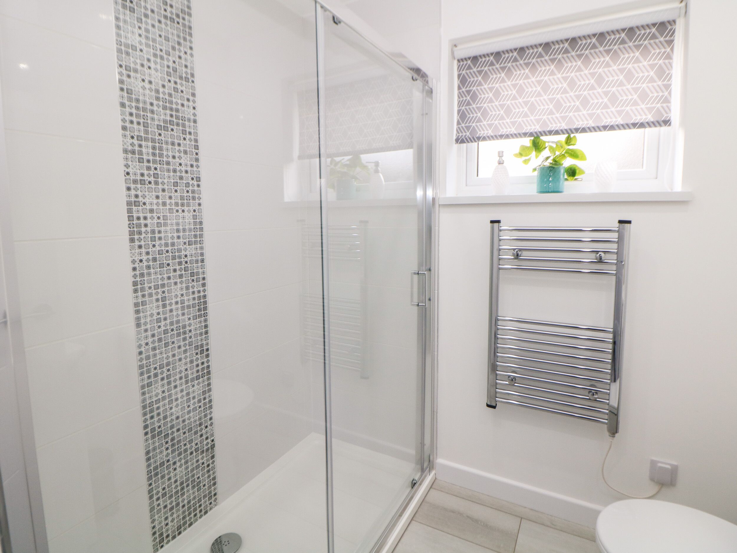 Um banheiro moderno com box de vidro, vaso sanitário branco e porta-toalhas.