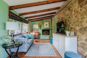 Una sala de estar acogedora con un sofá, una mesa de centro, una chimenea y una pared de piedra.
