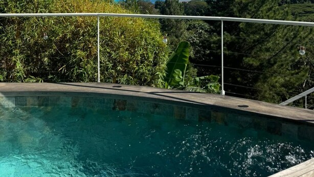 A swimming pool with a view of the ocean and surrounding greenery.