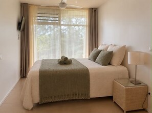 A bedroom with a bed, pillows, a bedside lamp, and a window with curtains.