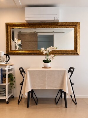 En matplats med ett bord dukat för två personer, en vit duk och en vas med vita blommor.