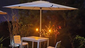 An outdoor patio with a table and two chairs under a large umbrella.