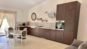 A modern kitchen with a dining area, featuring a round table, chairs, and a built-in oven.