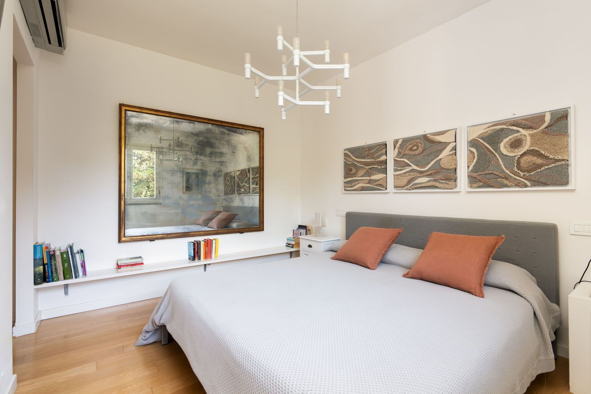 Een moderne slaapkamer met een groot bed, een inpandig raam en kunstwerken aan de wanden.