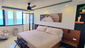 Ein Schlafzimmer mit einem großen Bett, einem Deckenventilator, einem Fenster mit Meerblick und einem Gemälde an der Wand.