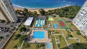 Ein Hochhaus-Hotel mit Pool, Tennisplätzen und Blick auf den Strand.