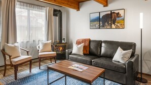 Ein gemütliches Wohnzimmer mit Kamin, Ledersofa, Holzstühlen und einem Couchtisch.