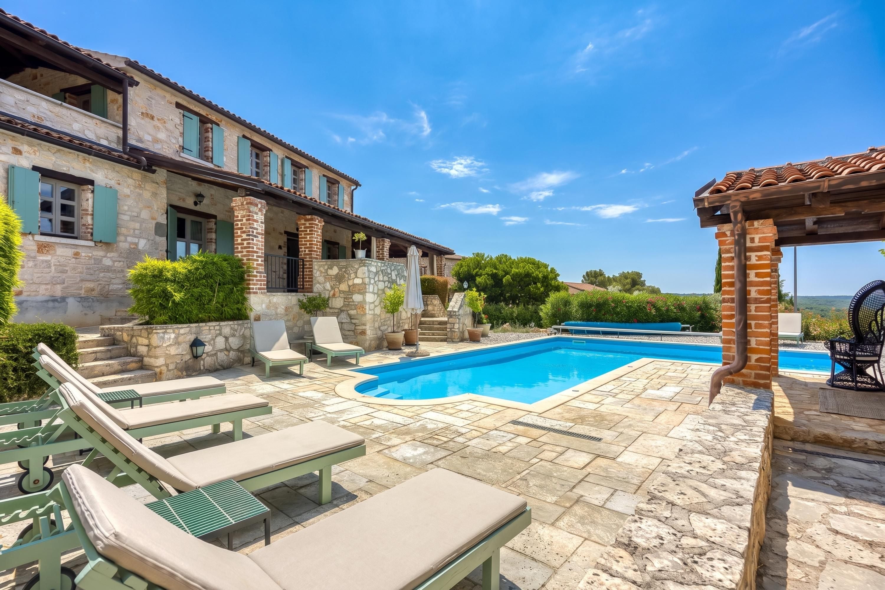 A stone building with a swimming pool, outdoor seating, and a view of the landscape.