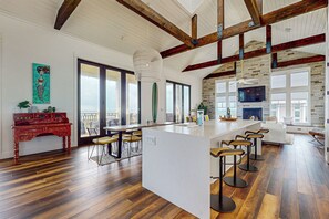 Un'ampia cucina con una grande isola, pavimento in legno e un soffitto alto con travi a vista.