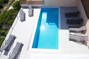 Ein Pool auf dem Dach mit Liegestühlen und Blick auf die umliegende Grünfläche.