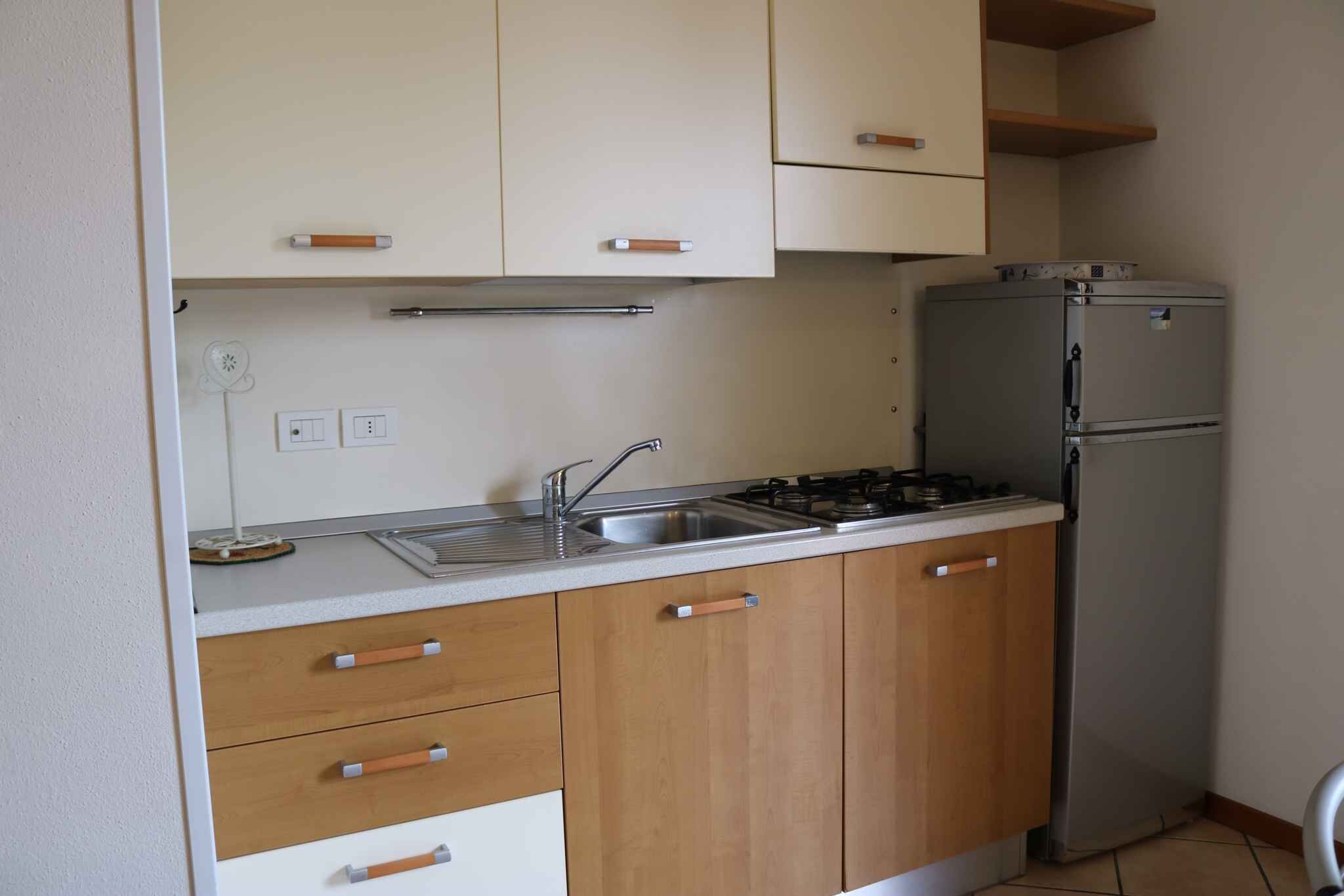 A compact kitchen with wooden cabinets, a stainless steel sink, and a built-in refrigerator.