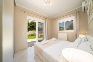 Een slaapkamer met een groot bed, een raam en uitzicht op een tuin.