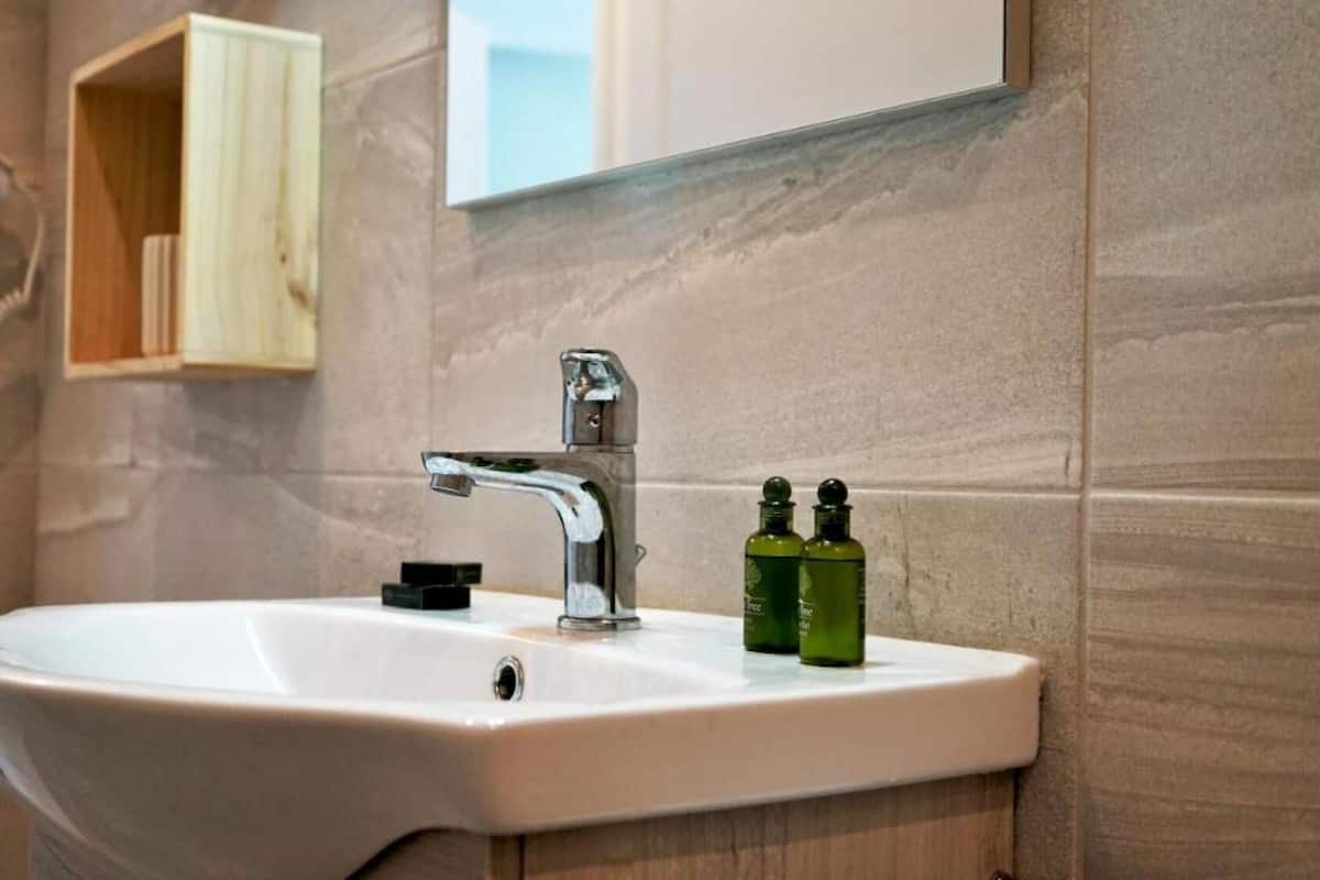 A bathroom sink with a modern faucet, a mirror above it, and a wooden cabinet to the left.