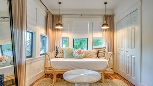 Ein Zimmer mit Bett, einem kleinen Tisch und einem Fenster mit Vorhängen.
