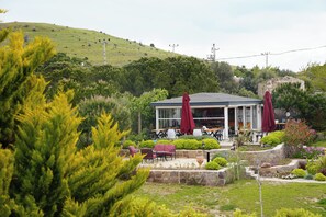 Um edifício com área externa para sentar, rodeado por vegetação e uma paisagem montanhosa.