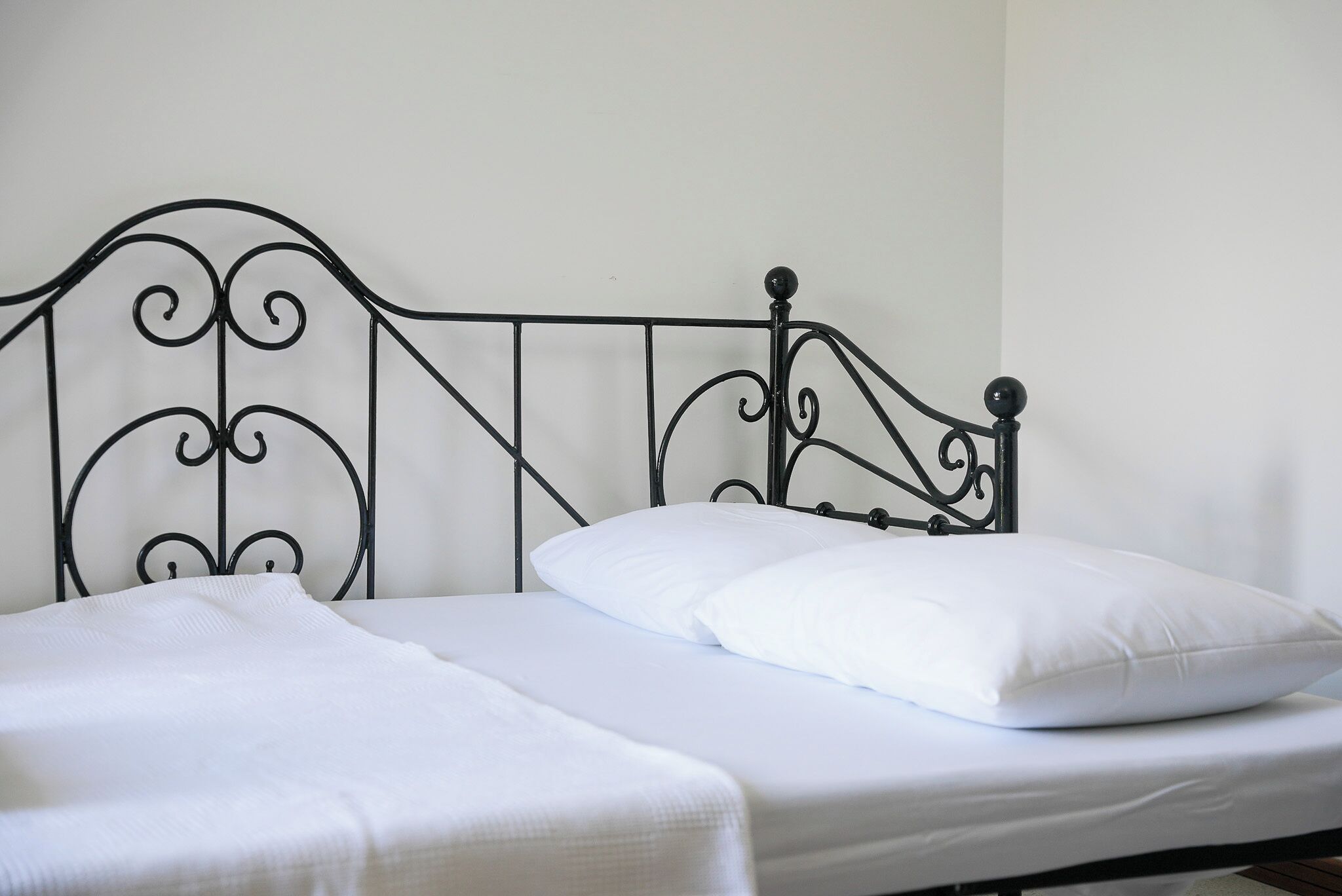 A single bed with a metal frame and white bedding.