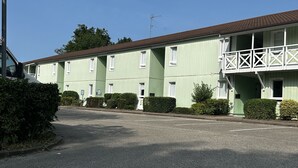 A green building with multiple windows and a balcony. - Hôtel Gex (Gex)
