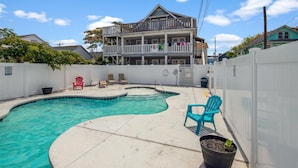 A swimming pool with a wooden deck, lounge chairs, and a white fence. - Cozy 1 bedroom condo, Downtown, with a pool, close to the beach and the famous OC boardwalk (Ocean City)